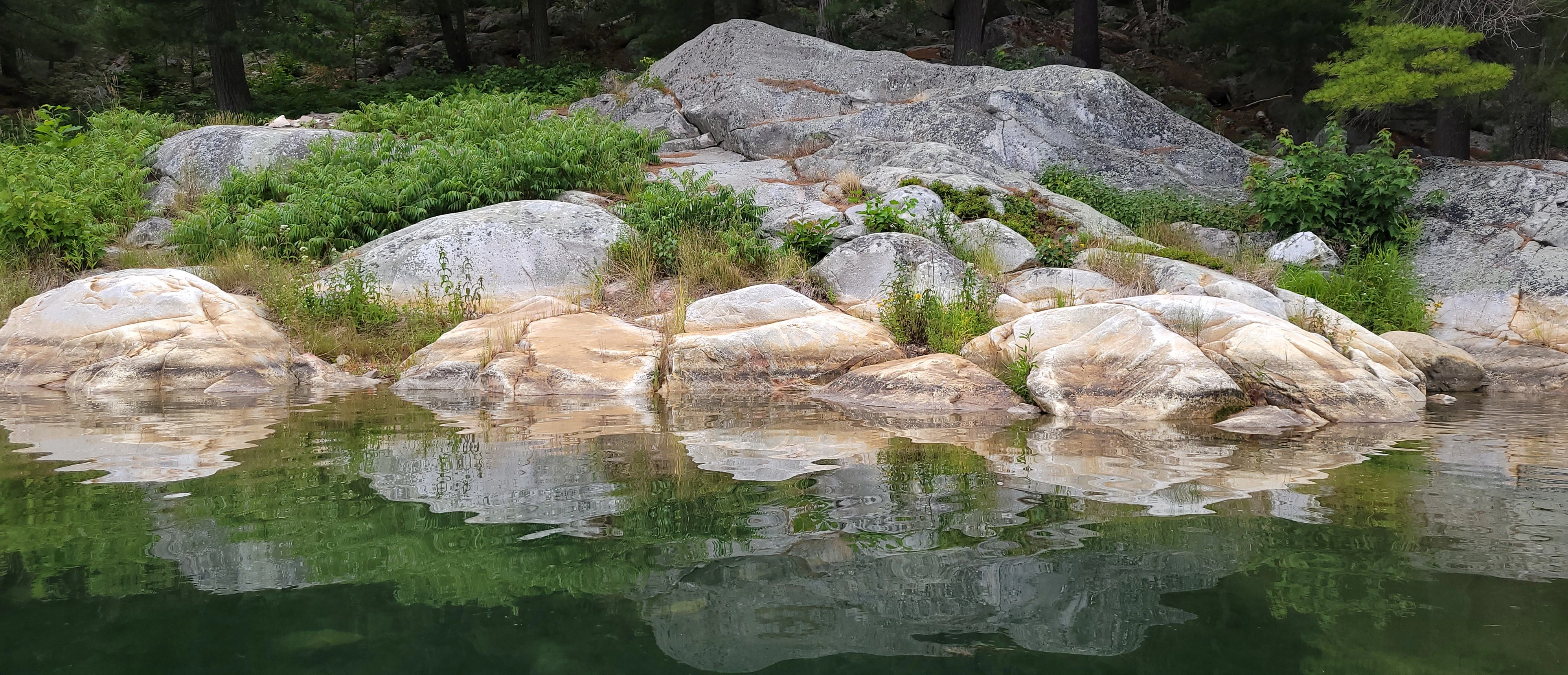 White quartzite cliffs reflected in calm water at Indian Head Cove